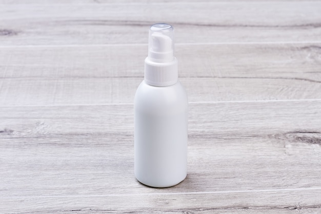 Moisturizer bottle on wooden background. Plastic bottle with cap. Take care of your skin.