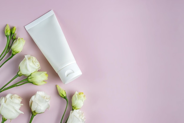 Moisturizer hand cream white plastic tube mockup on pink trandy\
background with eustoma flowers blank skin care beauty product\
packaging