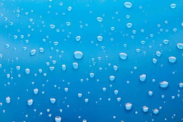 Moisturizing liquid blue drops on pastel background. Cosmetic toner or Water Drops. Hyaluronic serum Bubbles close-up. The texture of gel cream.