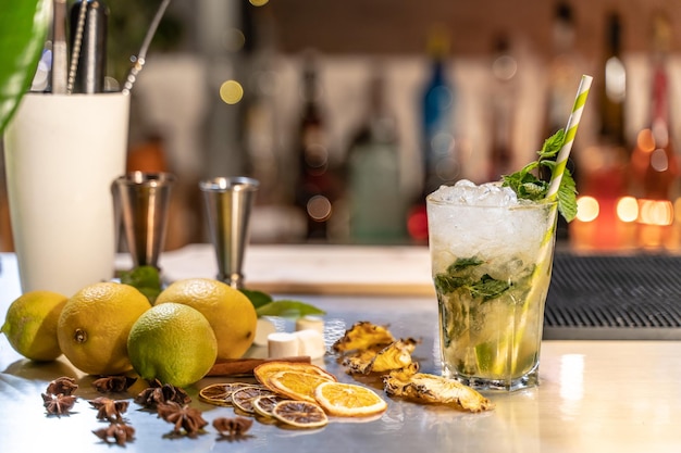 Mojito cocktail on bar counter with lemons limes and species with copy space for text