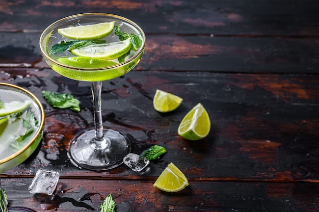 Mojito cocktail drink with lime, Ice and mint. Black wooden background. Top view. Copy space.