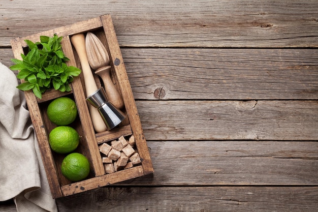 Mojito cocktail ingredients and bar accessories box on wooden table Top view with copy space