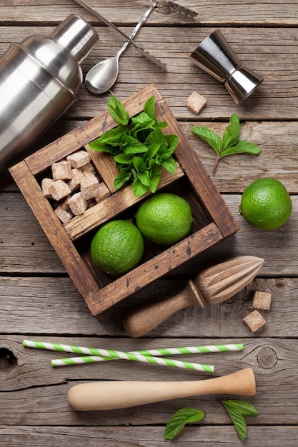 Mojito cocktail ingredients and bar accessories box on wooden table Top view