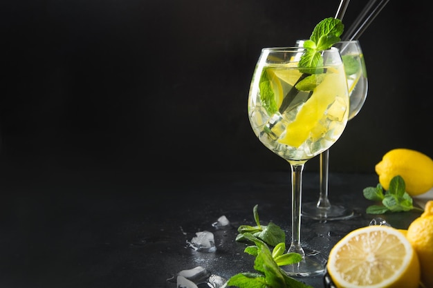 Mojito cocktail or lemonade with lime and mint in glass on black Summer drink