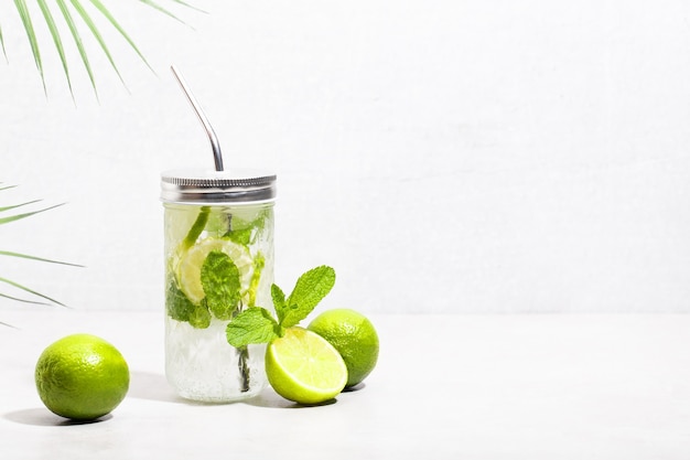 Mojito cocktail with lime and mint in a highball and a metal tube