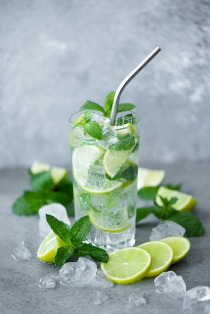 Mojito cocktail with mint, lime and ice in a tall on a grey background