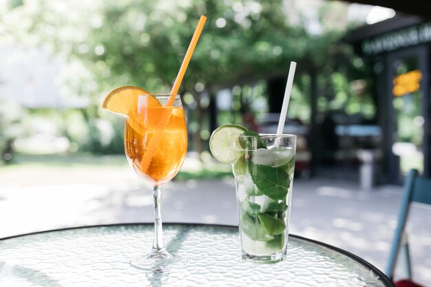 Mojito en aperol op een glazen tafel Aperol en mojito Cocktails in de zomer Heerlijke cocktails in de zomer