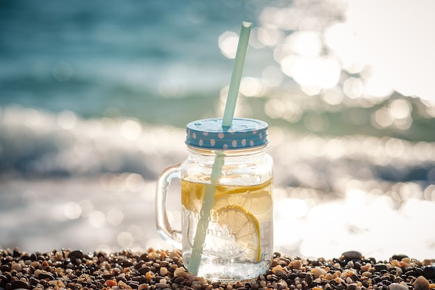 海岸のガラス瓶の中のモヒート。海での夏のビーチの楽しみ