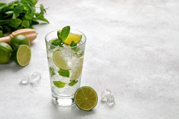 Mojito ijskoude zomerdrank glas koude tonic met limoen limonade met ijs en munt op grijze tafel