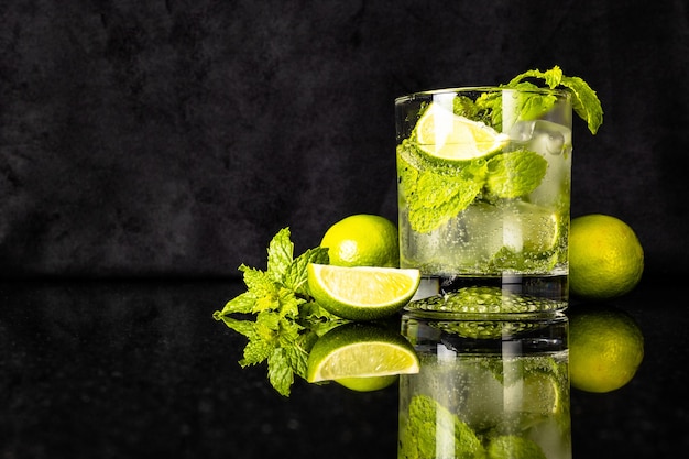 mojito iwith lime and mint next to a glass with reflection