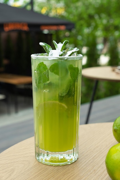 Mojito and limes on a street cafe table against greenery