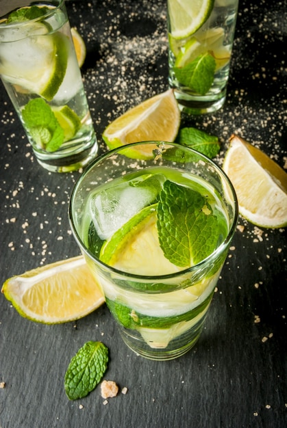 Mojito of limonade met stukjes citroen limoen muntblaadjes op een zwarte betonnen ondergrond met ijs c