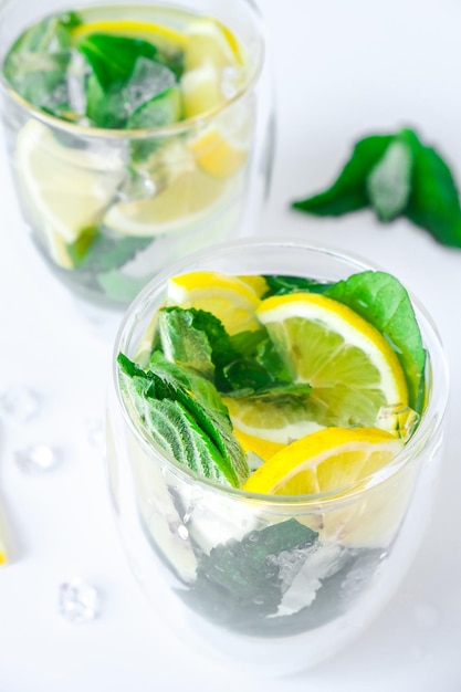 Mojito refreshing cocktail alcohol drink Lemonade with lemon and mint leaves on light background Ice cubes Summer refreshing detox drinks Clean eating healthy lifestyle concept