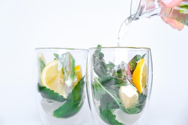 Mojito verfrissende cocktail gieten alcohol drankje Limonade met citroen en muntblaadjes op lichte achtergrond ijsblokjes Zomer verfrissende detox drankjes Schoon eten gezonde levensstijl concept