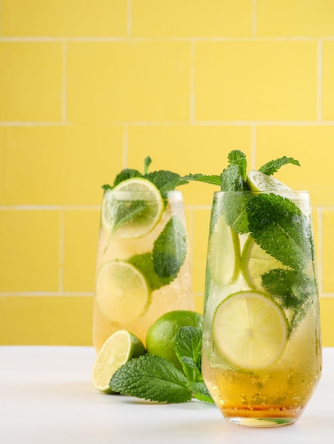Foto bevanda lunga al rum mojito o mojito vergine con menta fresca, succo di lime, zucchero di canna e soda su sfondo giallo