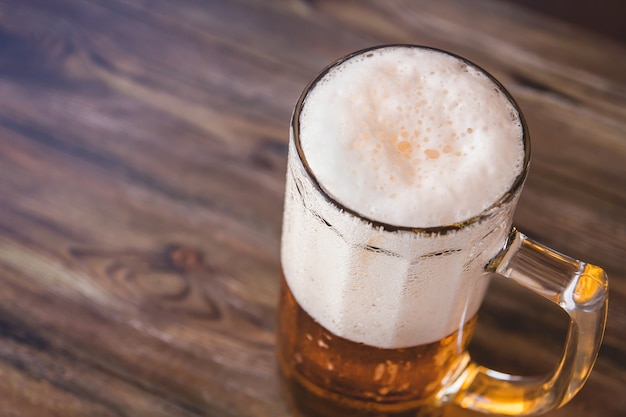 Foto mok bier met schuim op een houten tafel