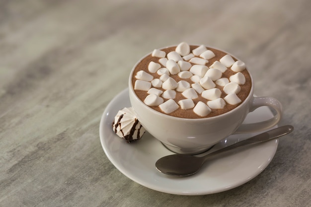 Mok koffie met marshmallows op porseleinen plaat op lichte achtergrond