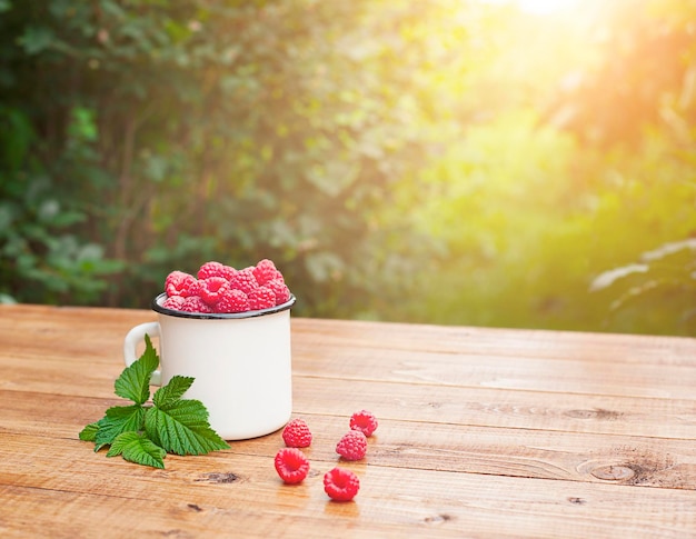 mok met frambozen op tafel buiten in de tuin in de zon