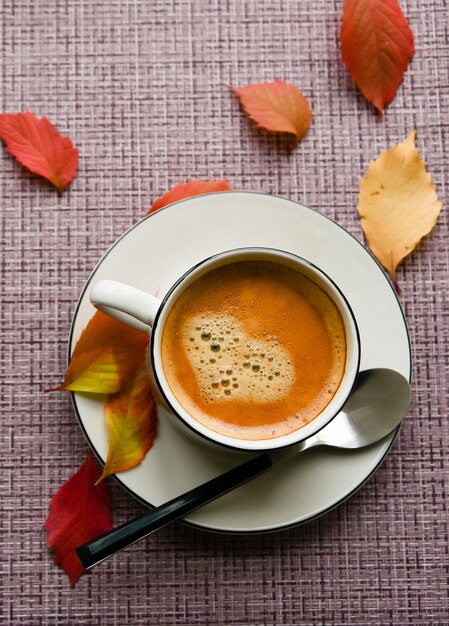 Mok met koffie met gele bladeren herfstsfeer