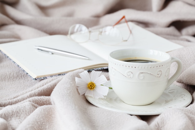 Mok ochtendkoffie in bed, het lezen van een boek, lentebloem