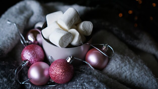 Mok warme chocolademelk met marshmallow op een donkere achtergrond, warme winterkerstdrank met roze kerstballen - close-up foto