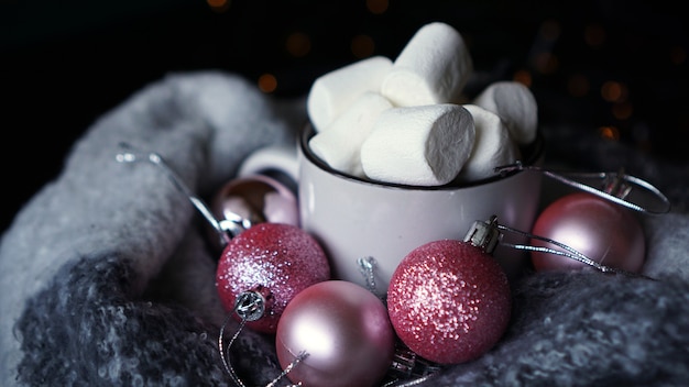 Mok warme chocolademelk met marshmallow op een donkere achtergrond, warme winterkerstdrank met roze kerstballen - close-up foto