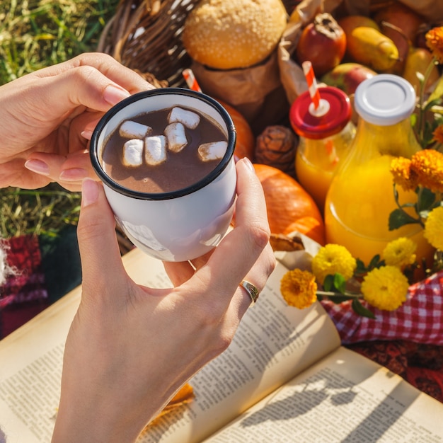 Mok warme chocolademelk of cacao met marshmallow in handen van een vrouw