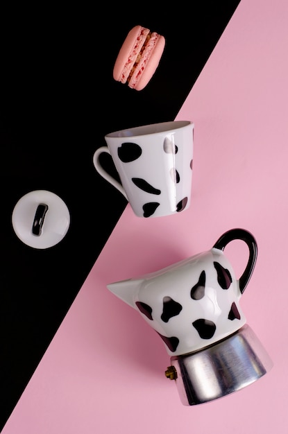 Moka coffee pot. Italian coffee maker with a cup and macaroon on pastel pink and black 