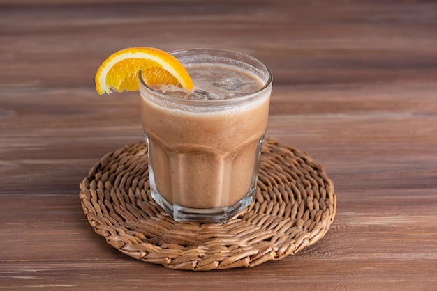 Mokkakoffie met sinaasappel en kokosmelk in een glas op een houten tafel