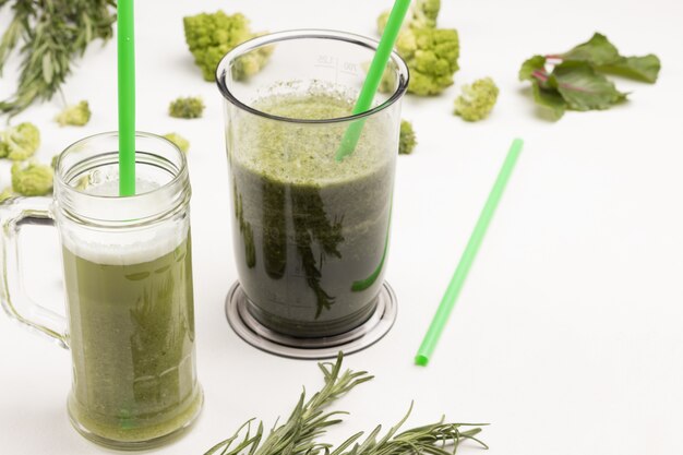 Mokken en blenderkom met groene groentesmoothies.