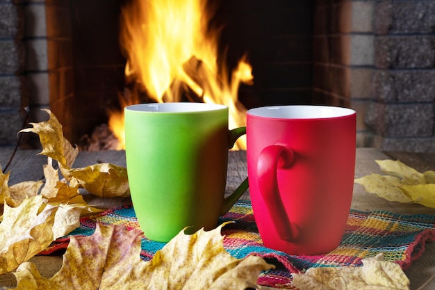 Foto mokken thee of koffie en herfstbladeren voor een gezellige open haard in het landhuis