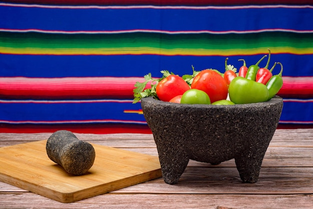 Molcajete with vegetables on wooden table Ingredients for a hot sauce