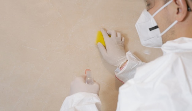 Mold removal A man cleans mold from a wall using a sprayer and a sponge Insect and mold removal company Cleaning Specialist