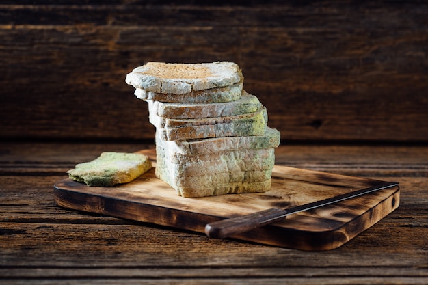 Moldy bread on wooden table 