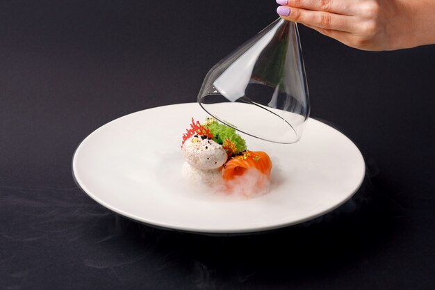 Molecular cuisine gravlax trout with garlic ice cream on a black background