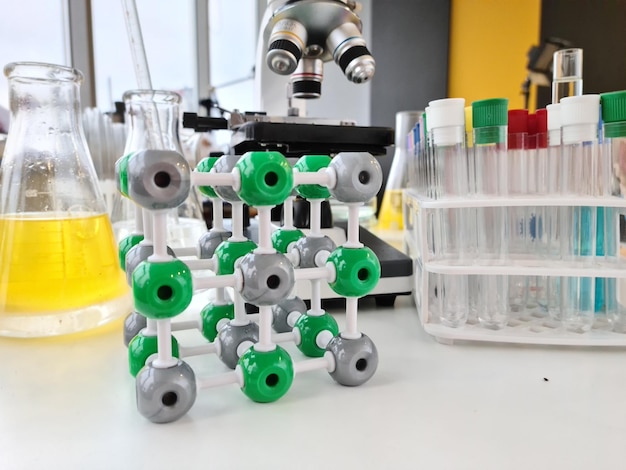 Молекулярная структура микроскопа и колбы с маслом на столе в лаборатории