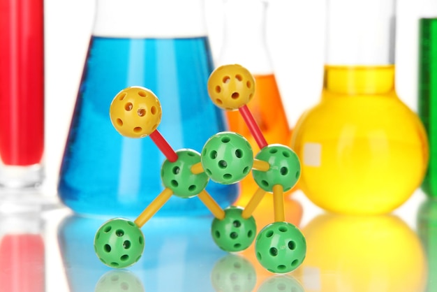 Molecule model and test tubes with colorful liquids close up
