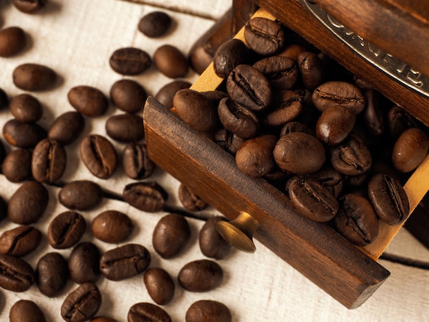 Molen van de close-up de uitstekende koffiemolen met koffiebonen op een donkere en lichte houten achtergrond.