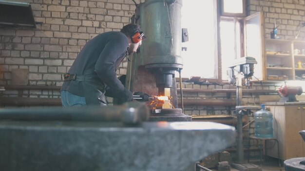 molten metal is processed under pressure in the hands of a blacksmith wide angle