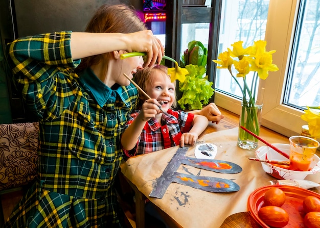 Mom amd boy drawing the ears of a handmade Easter bunny made of cardboard Preparation for the celebration of the Easter holiday