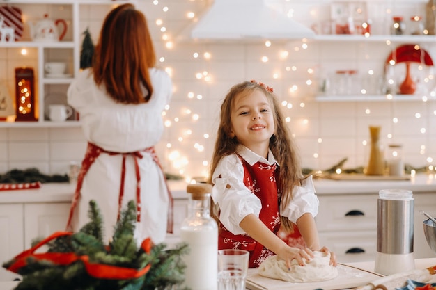 お正月のキッチンにいるママと娘が一緒にクリスマスクッキーの生地を準備します。