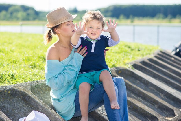 写真 ママと幼い息子が公園を散歩し、晴れた夏の日に楽しんでいます