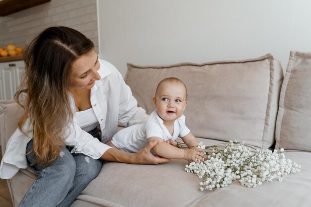 mom and baby on the bed with a bouquet of white flowers