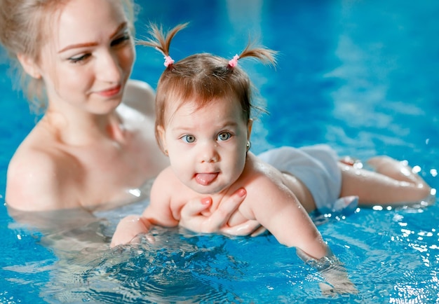 엄마와 아기는 수영장에서 수영합니다.