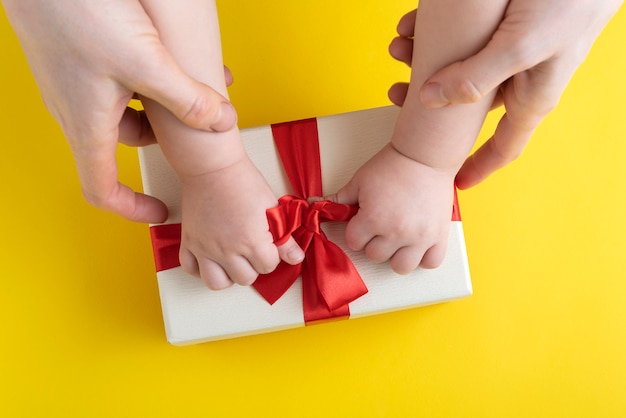 Mom and baby untie bow on the gift. Top view.