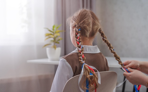 Mom braids her daughter's pigtails with ribbons