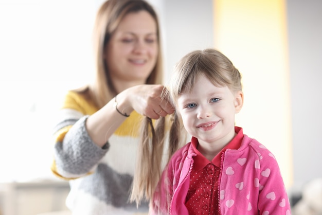 Mom braids a little girl's pigtail closeup