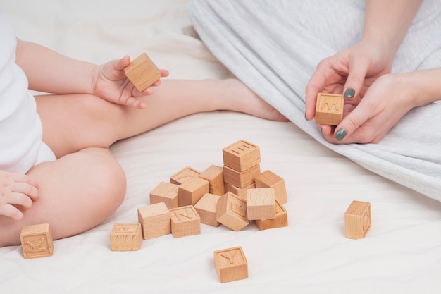 Mom and child are learning the English alphabet closeup The child plays with wooden cubes with English letters The concept of early development preschool education at home Educational games