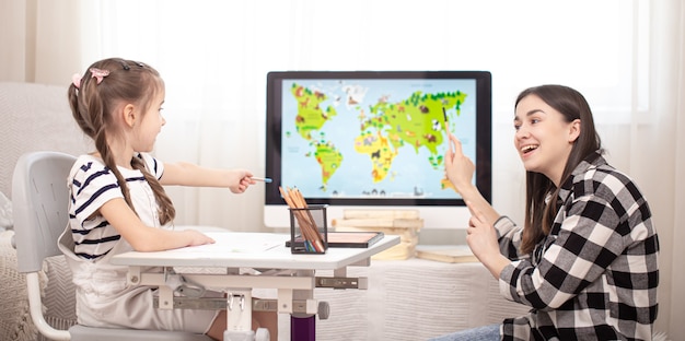 Mom and child do homework with geography using a map. Home schooling and education  