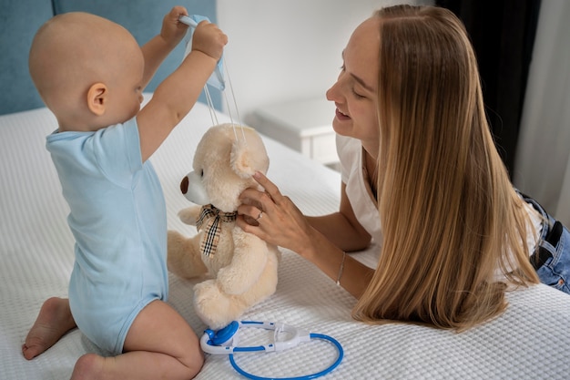 Foto mamma e bambino che giocano con l'orsacchiotto